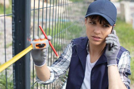 a female worker on the phone measuring fence