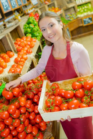 a shop assistant restocking tomatoes