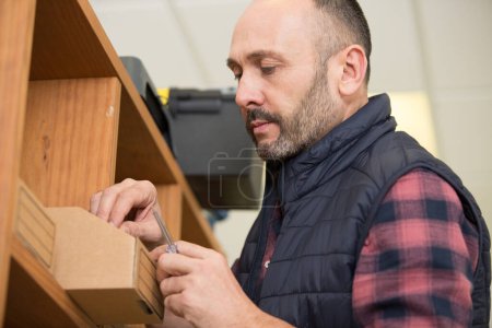 portrait of craftsman with in hand near shelves in carpentry