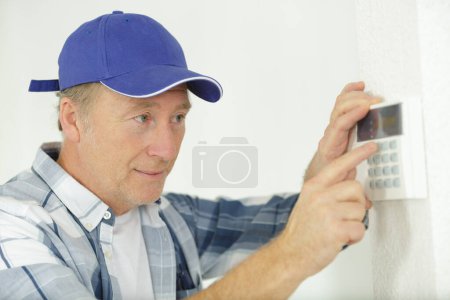 mature male worker installing alarm system