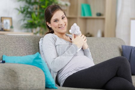 pregnant lady on sofa holding teddy bear