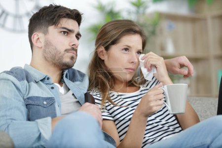 sad couple watching football match on television at home