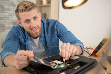 jeune homme démantelant un ordinateur portable