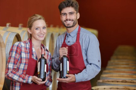 man and women holiding wine bottles in cellar