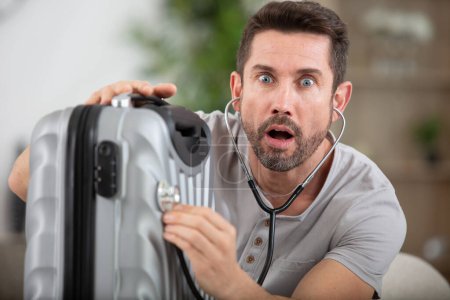 man using stethoscope on his suitcase