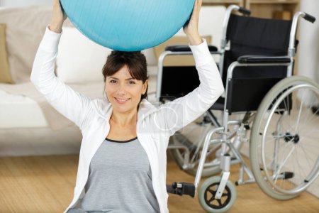 woman in wheelchair is doing sport with ball