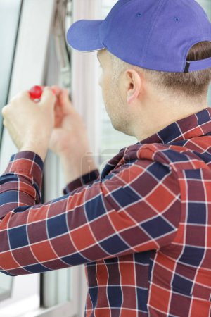 construction worker repairing window in house