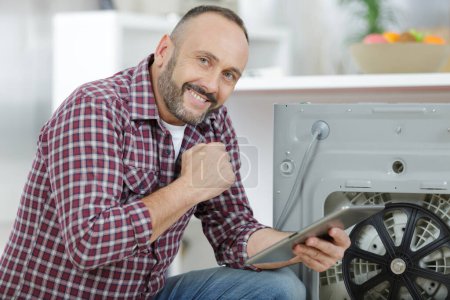 man using digital tablet at laundry