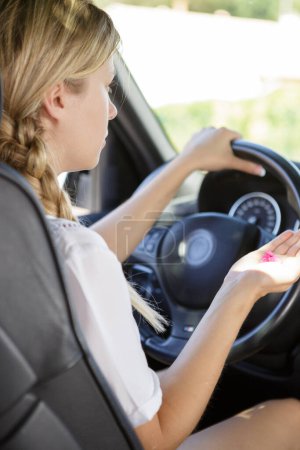woman taking pills while driving