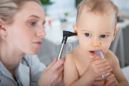 doctor examines kid ear with otoscope in a pediatrician room
