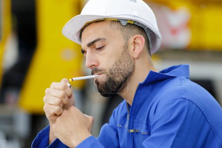 lazy worker is walking with cigarettes through the construction site