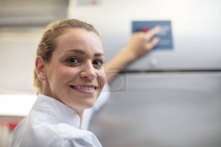beautiful woman in white overalls next to industrial food equipment