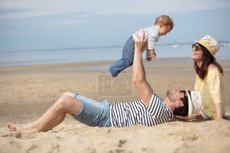 baby laughing while playing with his dad on the beach