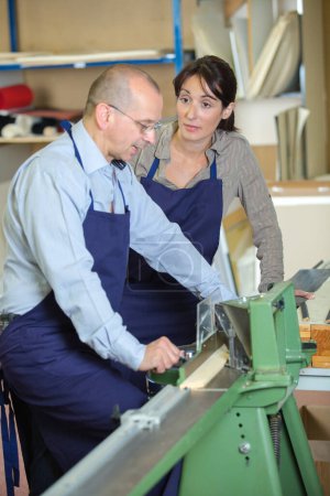 female worker watching coworker use woodworking machine annoyed expression