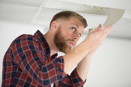 man replacing the light bulb on the ceiling