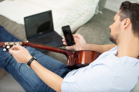 man using a smartphone app to learn guitar