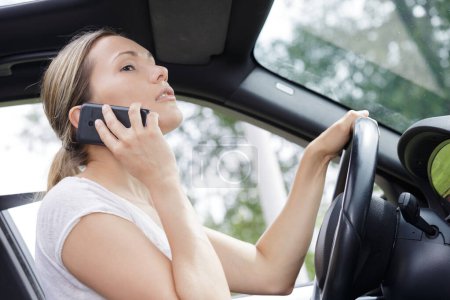 Femme utilisant son téléphone à la main tout en conduisant la voiture
