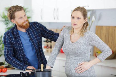 mujer embarazada en casa experimentando algunos dolores en el abdomen