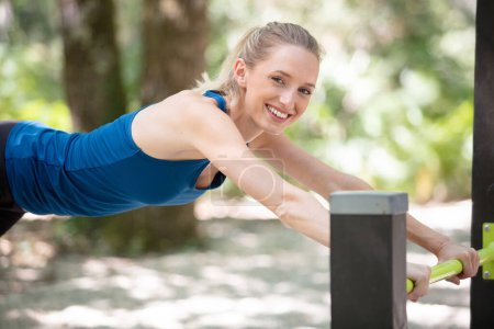 beautiful young woman exercising on outdoor parallel bars doing push-ups