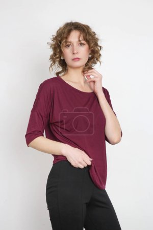 Photo for Serie of studio photos of young female model wearing simple comfortable outfit, organic cotton burgundy blouse and black skinny trouserswith slits - Royalty Free Image