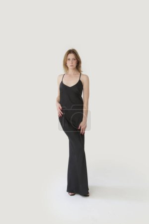 Female fashion model in long black silk camisole dress, studio shot.