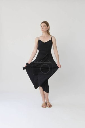 Téléchargez les photos : Serie of studio photos of young female model in comfortable yet stylish cotton black dress - en image libre de droit