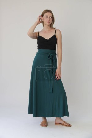 Téléchargez les photos : Serie of studio photos of young female model in comfortable yet stylish cotton outfit, black shit and emerald green skirt. - en image libre de droit