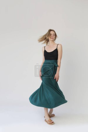 Téléchargez les photos : Serie of studio photos of young female model in comfortable yet stylish cotton outfit, black shit and emerald green skirt. - en image libre de droit