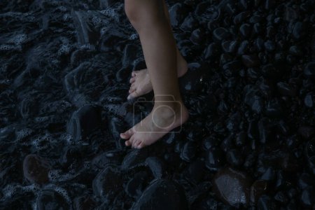 Photo for Child's feet barefoot on pebble beach near sea. Walking barefoot strengthens the muscles in children's feet and ankles, improving balance and posture and foster a connection with nature. - Royalty Free Image