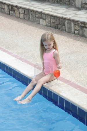 Photo for Adorable little girl having refreshment drinkby the poolside, hydratation and healhy diet during hot summer days - Royalty Free Image