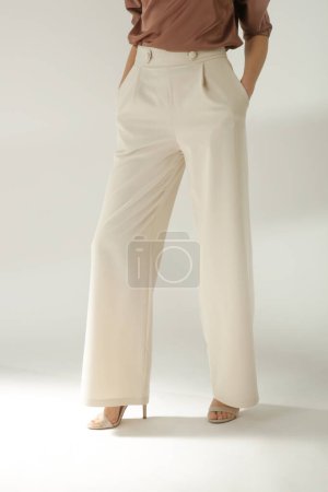 Female model wearing beige smart casual high rise trousers. Studio shot