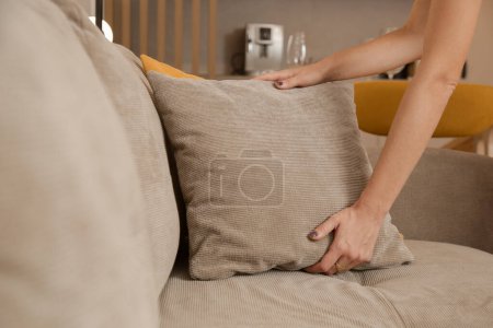 Photo for Woman arranging sofa cushion in living room - Royalty Free Image