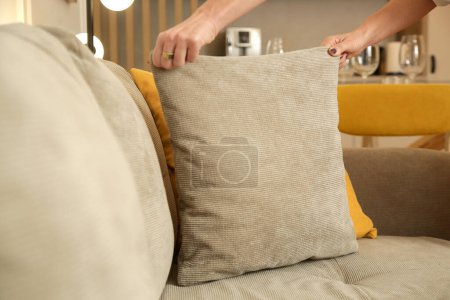 Photo for Woman arranging sofa cushion in living room - Royalty Free Image