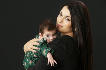 Photo for Portrait of young mother holding her little baby girl in green Christmas outfit, winter holiday, family memories, the first Christmas together - Royalty Free Image