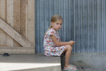 Téléchargez les photos : Petite fille agacée assise sur les marches de la rue - en image libre de droit