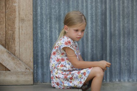 Téléchargez les photos : Petite fille agacée assise sur les marches de la rue - en image libre de droit