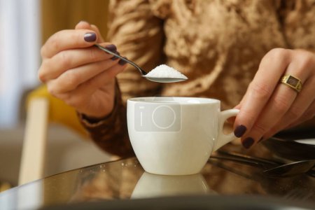 Photo for Woman adding sugar to hot drink - Royalty Free Image