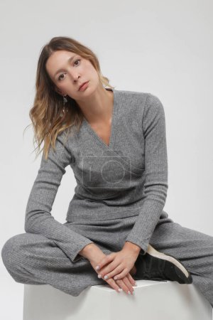 Serie of studio photos of female model in knitted grey set, autumn winter fashion collection.