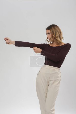 Serie von Studiofotos des jungen weiblichen Modells in bequemem lässigem Basic-Outfit, weinrotem Viskose-Bootsausschnitt-Hemd und beiger Hose