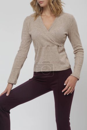 Serie of studio photos of young female model wearing basic flared purple trousers and knitted beige shirt, fall winter fashion collection
