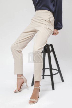 Das weibliche Model trägt beige schicke lässige Hochhaushosen. Studioaufnahme.