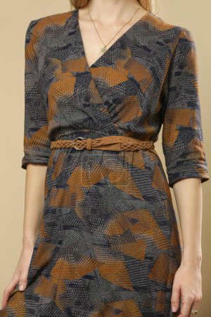 Serie of studio photos of young female model in viscose casual brown patterned dress for fall season