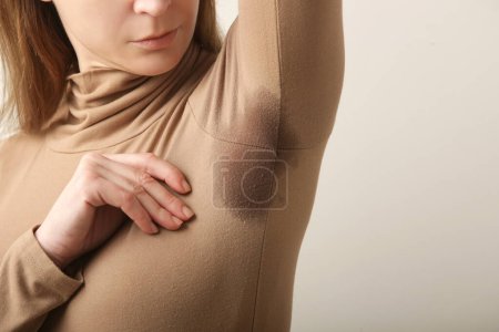 Foto de Imagen cercana de la mujer en cuello alto de algodón beige con parche de sudor debajo de la axila - Imagen libre de derechos