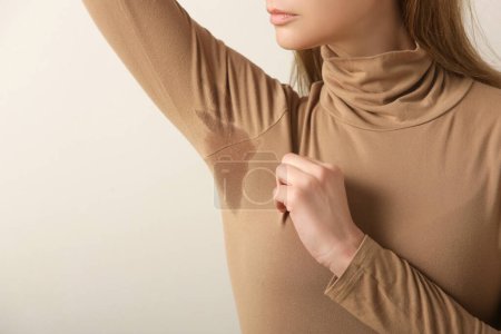 Foto de Imagen cercana de la mujer en cuello alto de algodón beige con parche de sudor debajo de la axila - Imagen libre de derechos