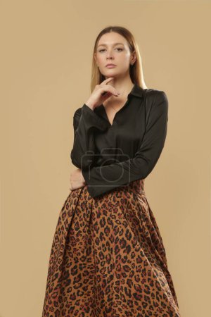 Photo for Serie of studio photos of young female model wearing black blouse with animal print midi skirt. Comfortable and elegant everyday fashion. - Royalty Free Image
