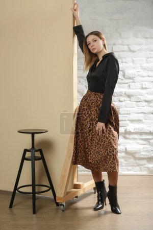 Photo for Serie of studio photos of young female model wearing black blouse with animal print midi skirt. Comfortable and elegant everyday fashion. - Royalty Free Image