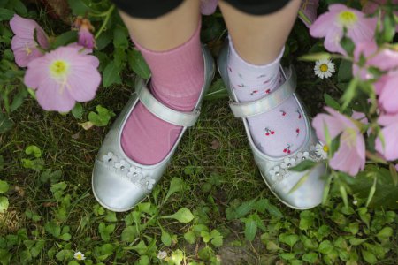 Kid wears different pair of socks. Child foots in mismatched socks standing outdoor.  Down syndrome awareness concept, odd socks day, anti-bullying week.