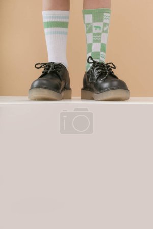 Kid wears different pair of socks. Child foots in mismatched socks, studio photography with copy space. Down syndrome awareness concept, odd socks day, anti-bullying week.