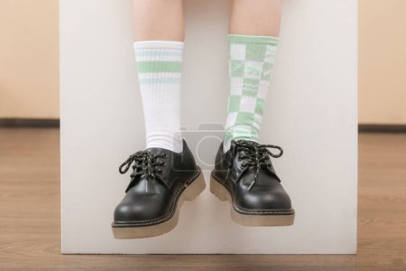 El chico usa un par de calcetines diferentes. Pies de niño en calcetines desiguales, fotografía de estudio. Síndrome de Down concepto de conciencia, calcetines extraños día, semana anti-bullying.