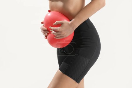 Young woman holding balloon as a sign of an stomach inflation, bloating and menstrual cramps concept